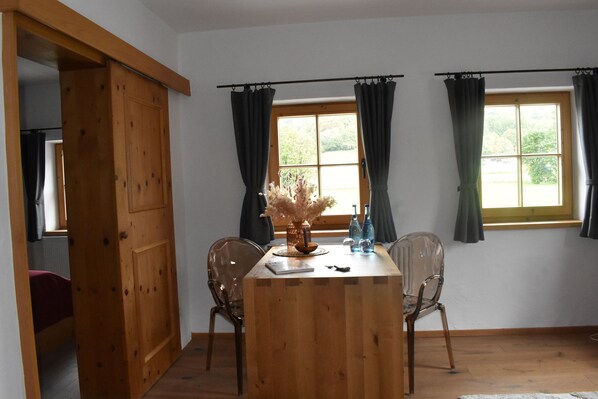 A wooden dining table with chairs, a vase with dried flowers, and a window with curtains. - Auwirt Aurach (Aurach bei Kitzbuehel)