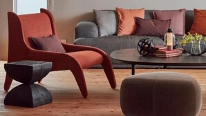 A modern living room with a red armchair, grey sofa, and a round coffee table.