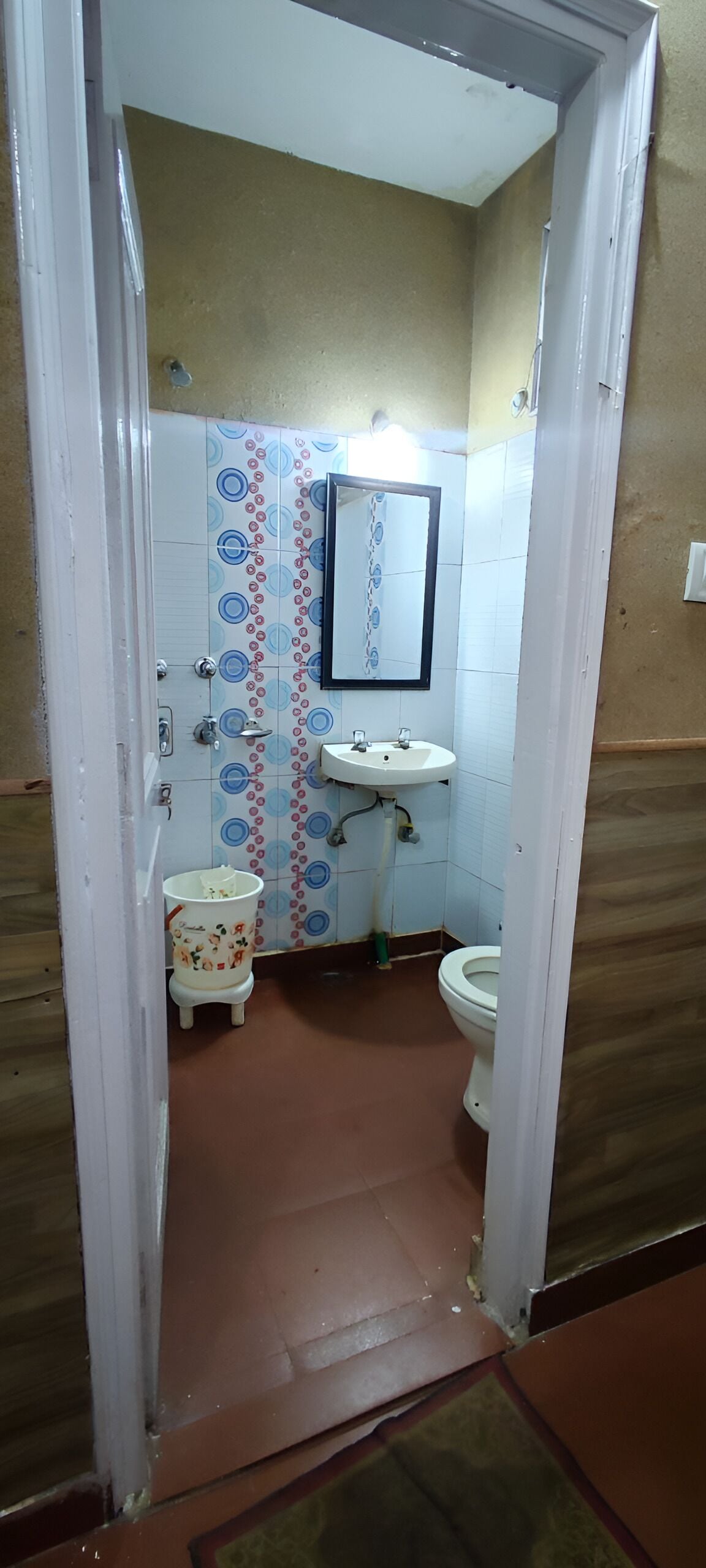 A bathroom with a tiled floor, a sink, a toilet, and a mirror.