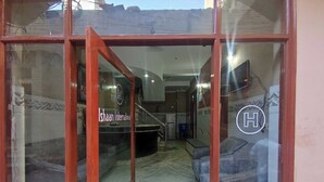 A hotel reception area with a reception desk, a staircase, and a green mat at the entrance. - Hotel Ishaan International (Reasi)