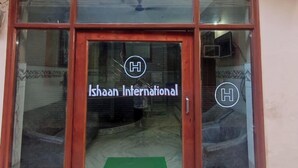 A building entrance with a glass door and windows, displaying the logo and name "Ishaan International". - Hotel Ishaan International (Reasi)