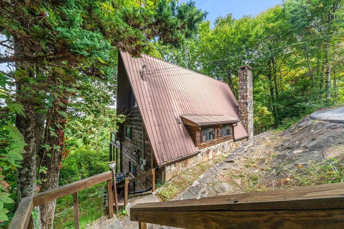 Une cabane avec un toit en pente, des fondations en pierre et une terrasse en bois.