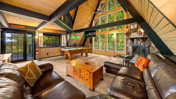 Une pièce chaleureuse avec une table de billard, un canapé en cuir et une cheminée.