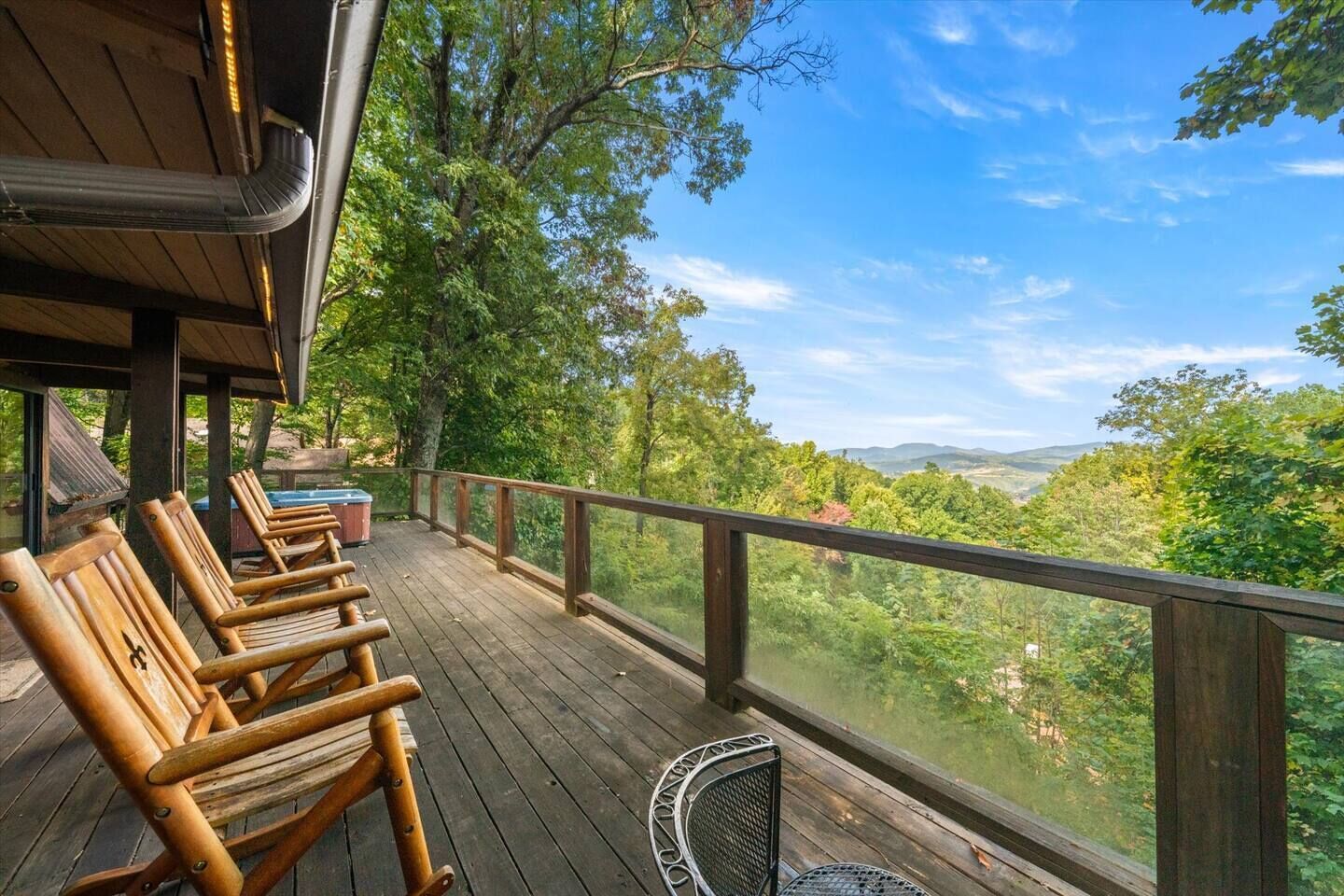 A wooden deck with outdoor seating and a view of a forested landscape.