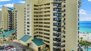 A multi-story hotel with a central courtyard, balconies, and a view of the beach. - Ocean Front Beach Condo (Panama City Beach)