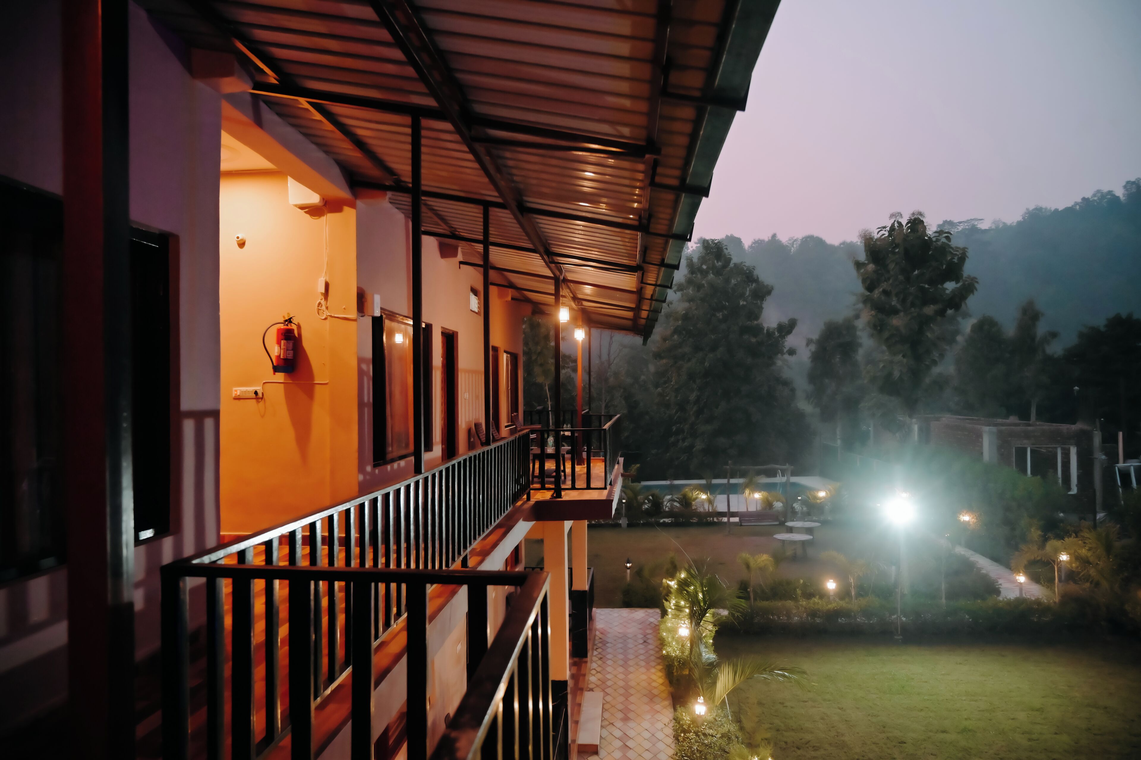 A building with a balcony, a fire extinguisher, and a well-lit outdoor area with lights.
