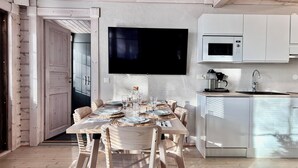 Une cuisine moderne avec des meubles blancs, un four à micro-ondes de marque Bosch et une machine à café.