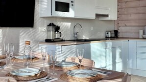 Une cuisine moderne avec des armoires blanches, un four à micro-ondes encastré et une machine à café.