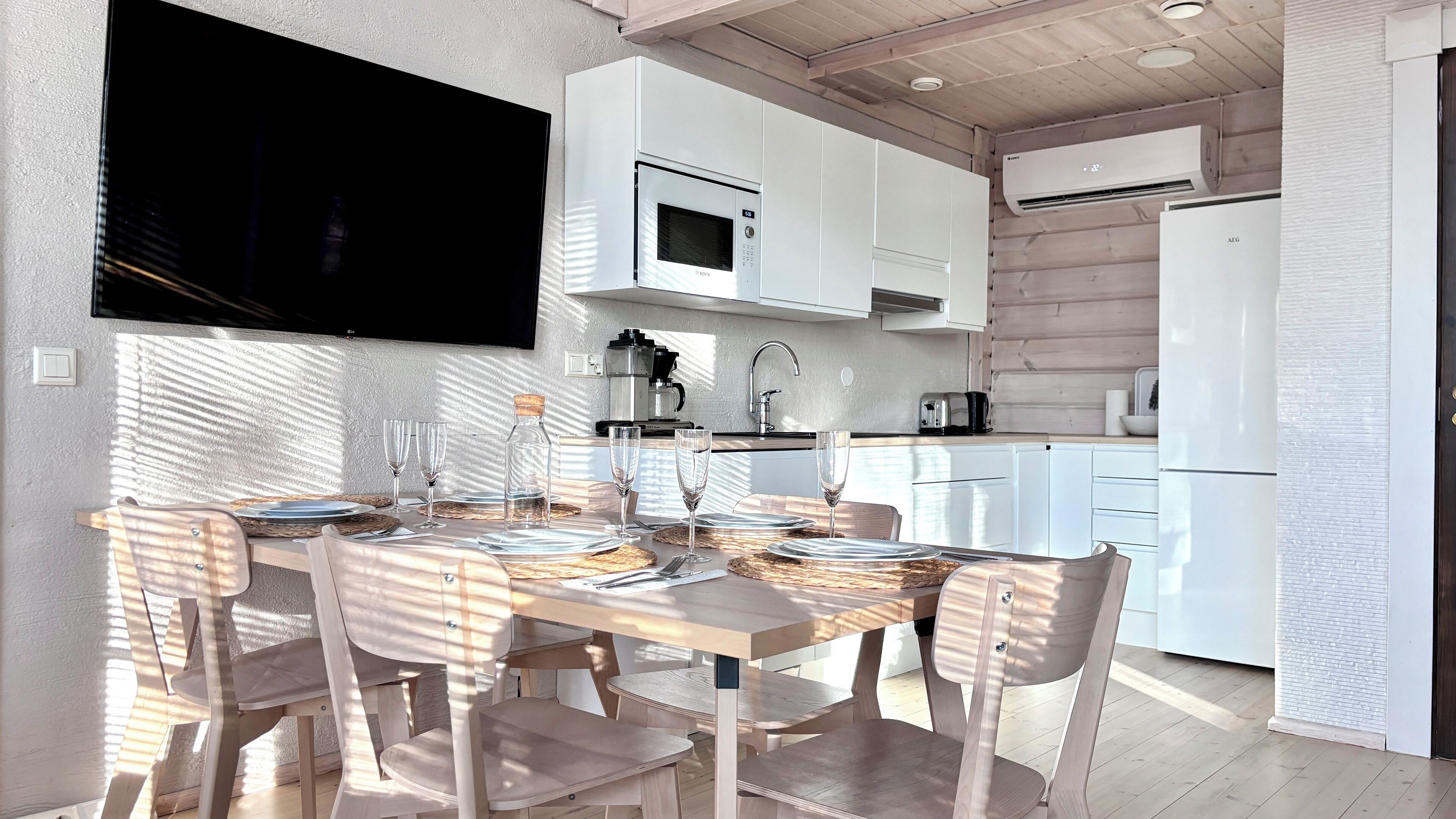 Een moderne keuken met witte kasten, een ingebouwde magnetron en een airconditioning.