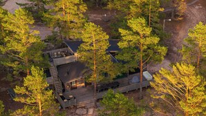 Une cabane moderne dotée d’une terrasse, entourée d’une forêt dense.