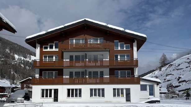 A multi-story building with balconies, surrounded by snow-covered landscape. - Apartments Atlas (Saas Grund)