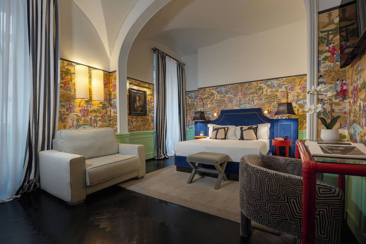 A bedroom with a bed, a sofa, a chair, and a small table.