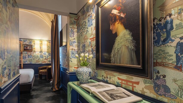 A room with a bed, a desk with a vase of flowers, and a large framed painting on the wall. - V Collection Condotti (Rome)