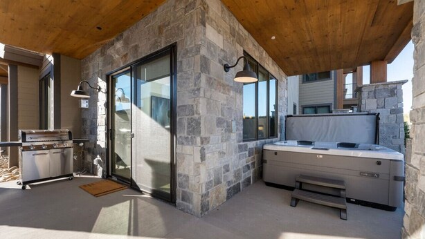 A modern outdoor kitchen with a stone wall, a grill, and a hot tub. - Downtown Fraser| Hot tub |Walkable (Fraser)