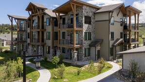 A multi-story residential building with a stone facade, multiple balconies, and a well-maintained lawn. - Downtown Fraser| Hot tub |Walkable (Fraser)