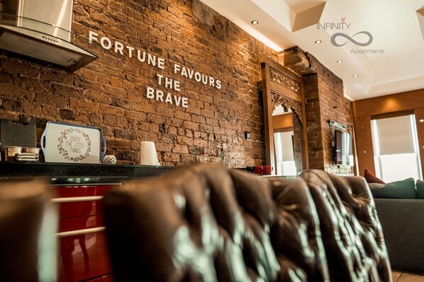 A modern interior with a brick wall, a kitchen area, and a sofa.