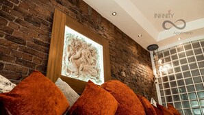A cozy living area with a brick wall, a framed artwork, and a row of orange cushions. - The Famous Floor Sleeps 26 and Group Acc Sleeps30 (Liverpool)