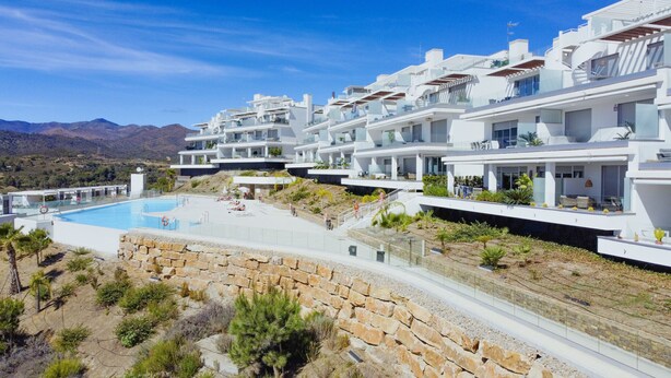 Un moderno resort con piscina, varios balcones y vistas a las montañas.