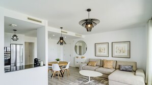 Una sala moderna con sofá, mesa de centro, mesa de comedor y zona de cocina.
