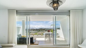 Una sala de estar moderna con un amplio ventanal corredero que da a una terraza exterior.