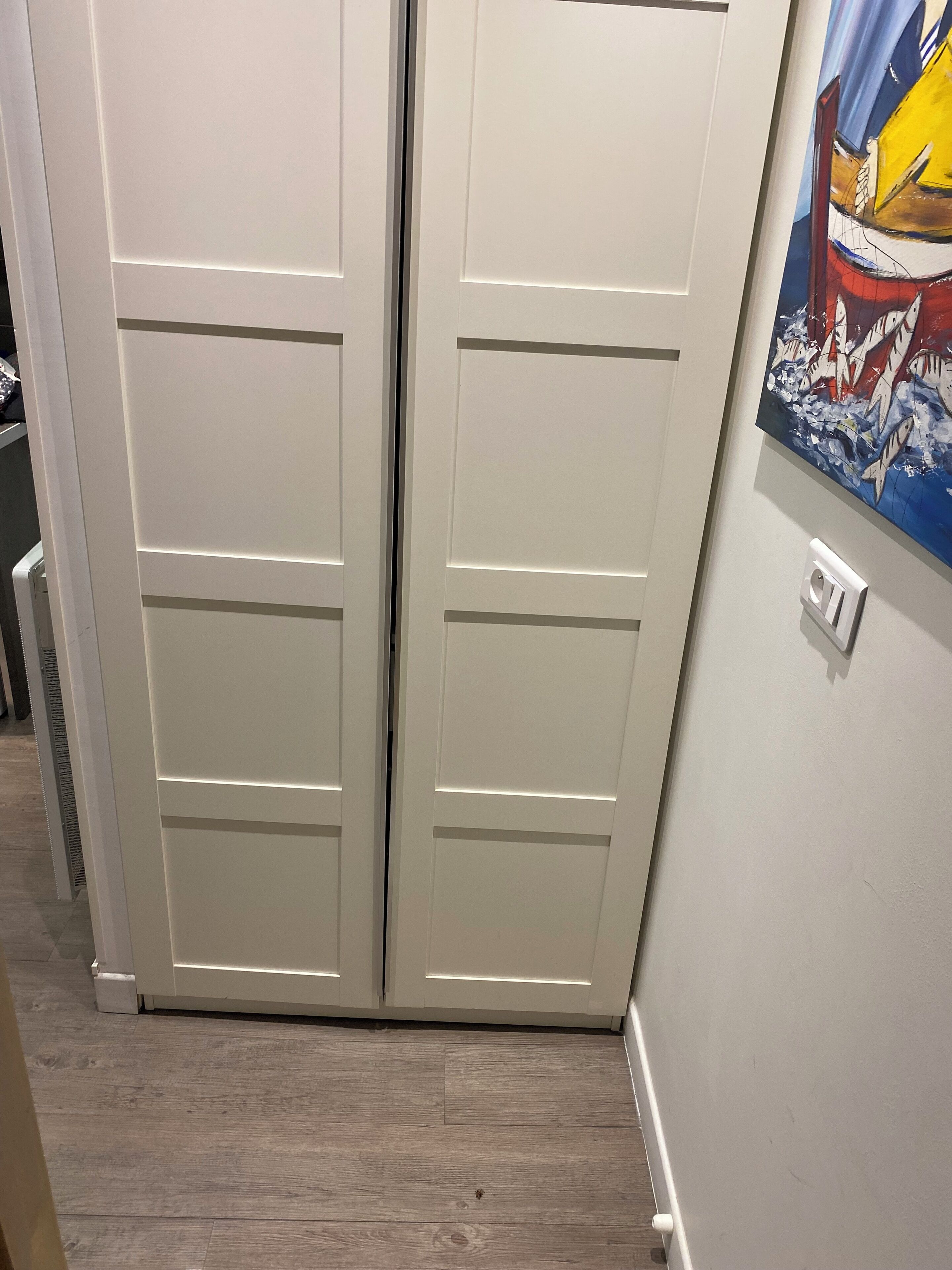 Un pasillo con una puerta blanca y un interruptor de luz en la pared.