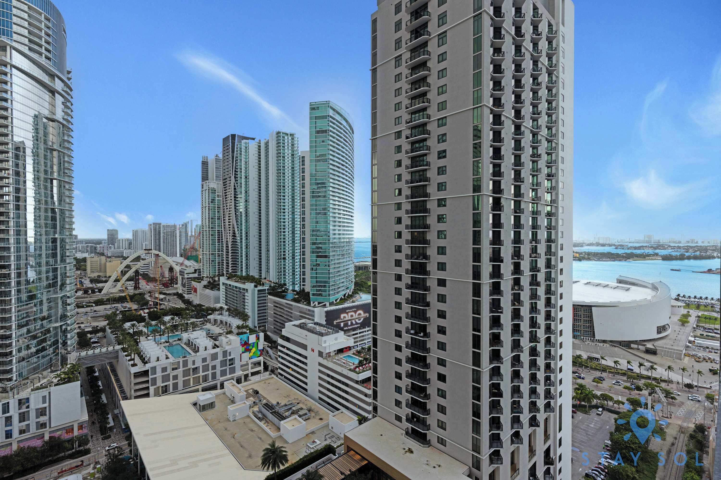 A high-rise building with a modern design, featuring multiple balconies and a rooftop area with a pool.
