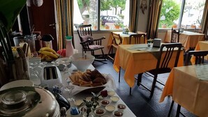 A dining area with tables set for a meal, a buffet with various food items, and a view of the street outside. - Hotel Puerto Las Palmas (Punta del Este)