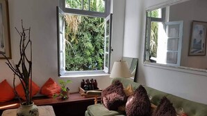 A cozy living room with a green sofa, a wooden coffee table, and a window with a view of greenery. - Hotel Puerto Las Palmas (Punta del Este)