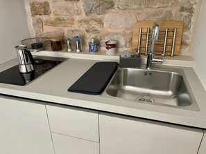 A modern kitchen with a built-in stove, a stainless steel sink, and a stone backsplash.