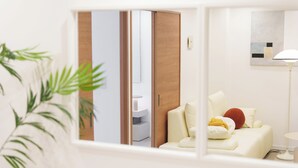 A modern hotel room with a white sofa, a small table, and a floor lamp. - TORA HOTEL Sumidagawa (Tokyo)