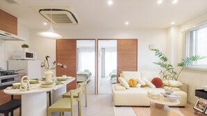 A modern living room with a sofa, coffee table, and dining area with chairs and a microwave.