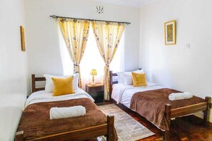 A room with two beds, a nightstand, a lamp, and a framed picture on the wall. - 3-bedroom standalone home,spacious garden with daybed,located in Karen, Nairobi. (Nairobi)