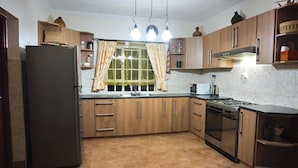 A kitchen with wooden cabinets, a stainless steel refrigerator, a gas stove, and a sink.