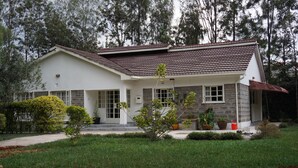 A two-story house with a tiled roof, a front porch, and a well-maintained lawn.