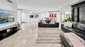 A spacious living room with a large flat-screen TV, two black leather sofas, a patterned rug, and a minimalist decor. - Sub-Penthouse Dream in Circle on Cavill (Gold Coast)