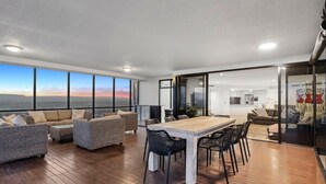 A spacious living area with a wooden floor, a large dining table, and comfortable seating. - Sub-Penthouse Dream in Circle on Cavill (Gold Coast)