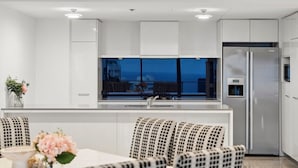A modern kitchen with white cabinetry, a stainless steel refrigerator, and a large window overlooking a balcony. - Sub-Penthouse Dream in Circle on Cavill (Gold Coast)