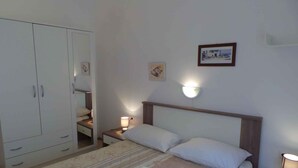 Ein Schlafzimmer mit Bett, Nachttischen, einem Kleiderschrank und Wandleuchten.