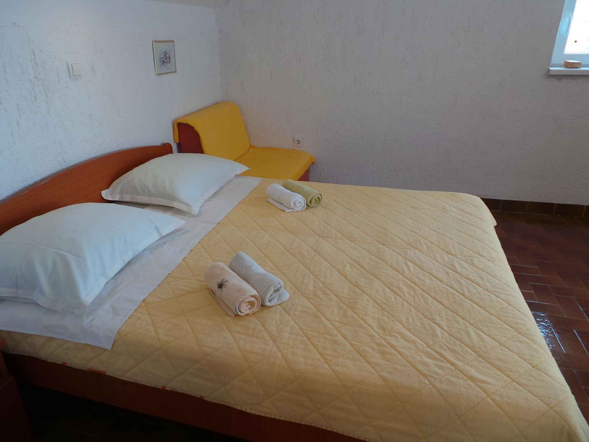 A bed with a quilted bedspread, two rolled towels, and two pillows.