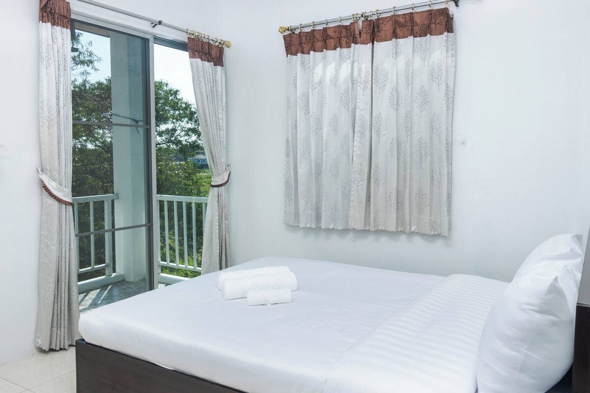 A hotel room with a bed, a balcony, and curtains.