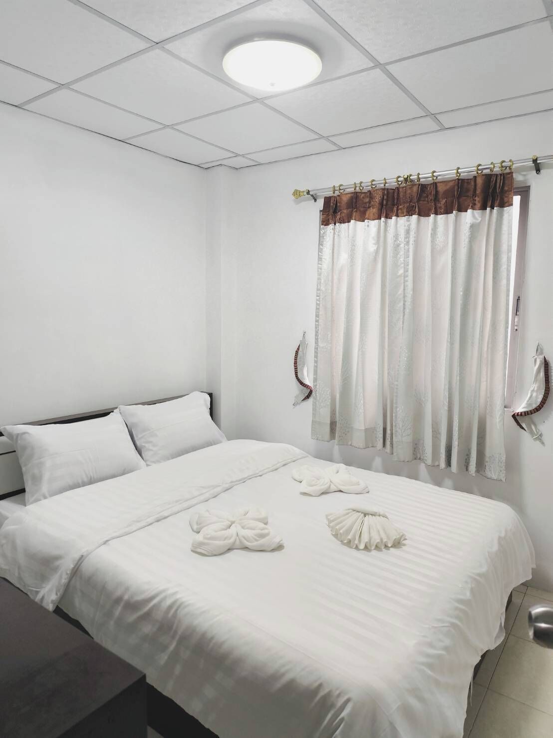 A neatly made bed with white linens and towels arranged on the bed.