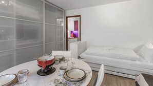 Et moderne hotelværelse med spiseplads, en sofa og udsigt til køkkenet.