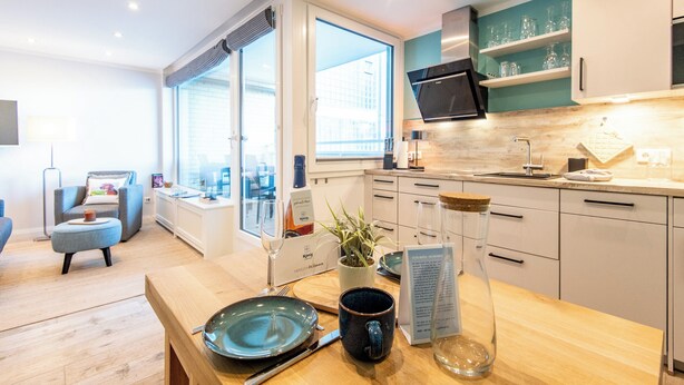 A modern kitchen with a dining area, a view through the window, and a cozy seating area.