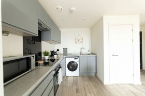 A compact kitchen with a microwave, sink, and washing machine. - Modern & Bright Central Liverpool 1 Bed Apartment (Liverpool)