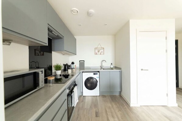 A compact kitchen with a microwave, sink, and washing machine.