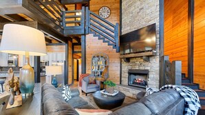 A spacious living room with a fireplace, leather sofas, a staircase, and a dining area. - Games, Hot Tub, Fire Pit, Pets, Times Like These (Broken Bow)