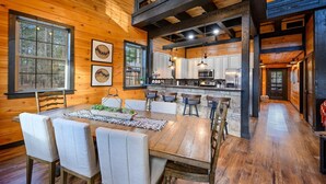 A rustic cabin interior with a dining area, kitchen, and a loft bedroom. - Games, Hot Tub, Fire Pit, Pets, Times Like These (Broken Bow)
