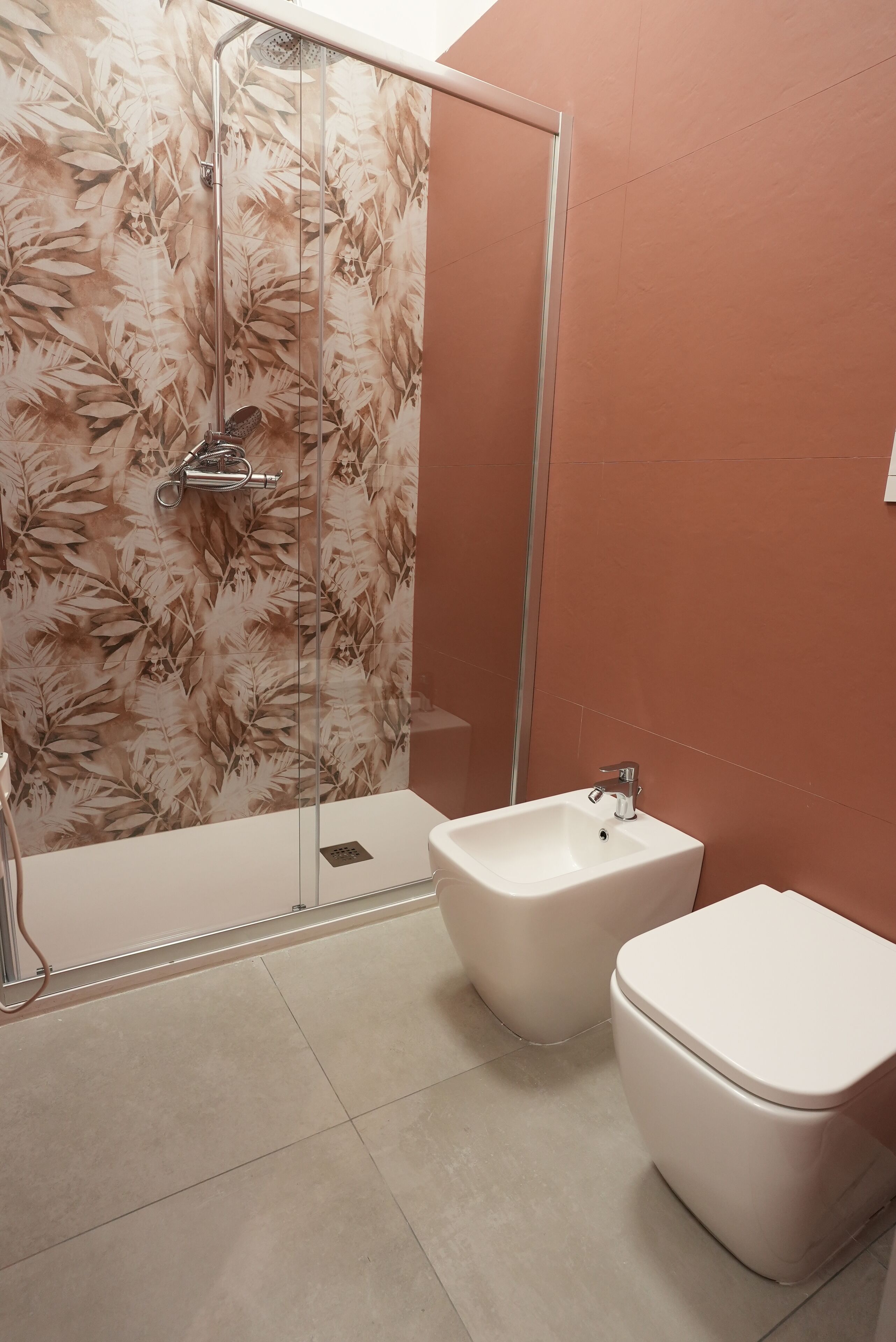 A bathroom with a shower, a bidet, and a toilet.