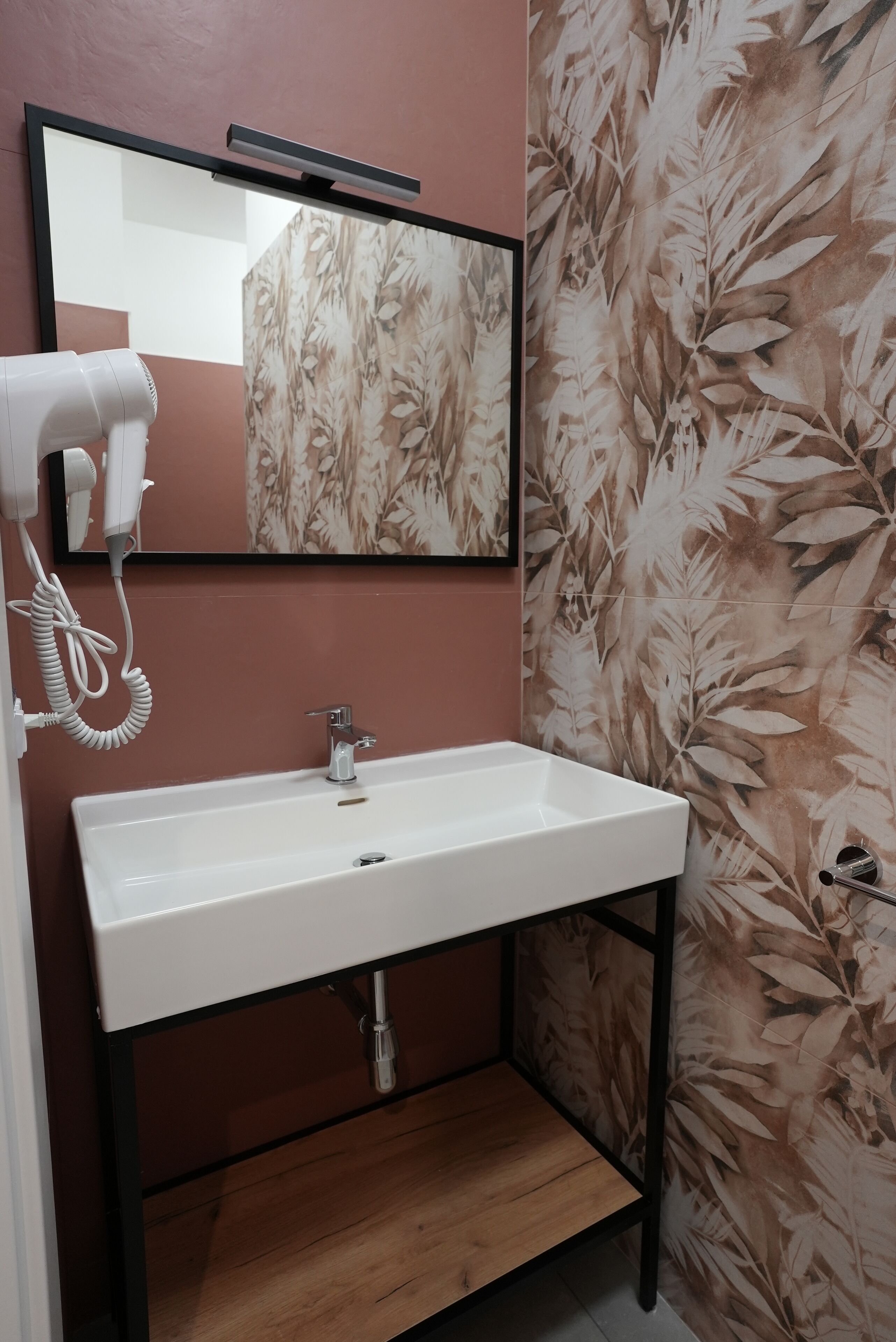 A bathroom with a white sink, a hairdryer, and a mirror.