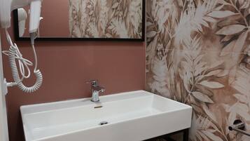 A bathroom with a white sink, a hairdryer, and a mirror.